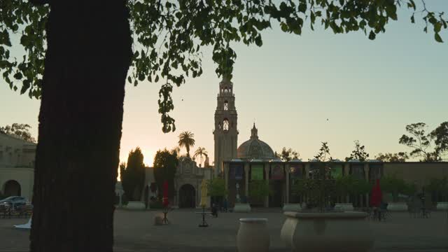 A park, palm trees and the buildings in Balboa Park, with people walking.