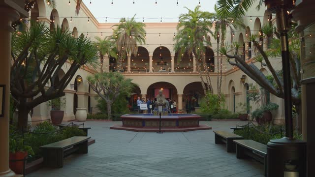 A park, palm trees and the buildings in Balboa Park, with a crowd gathered.