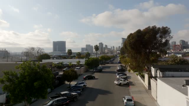 Low aerial view of a residential street, the skyline and palm trees in Barrio Logan.