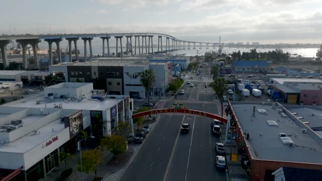 Low aerial view of the downtown streets, the bridge and the bay in Barrio Logan, with people walking.