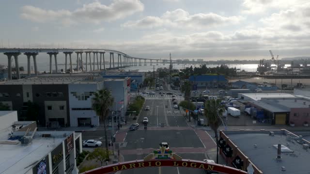 Low aerial view of the downtown streets, the bridge and palm trees in Barrio Logan, with people walking.