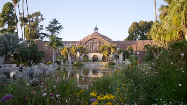 A park, palm trees and the buildings in Balboa Park, with people walking.