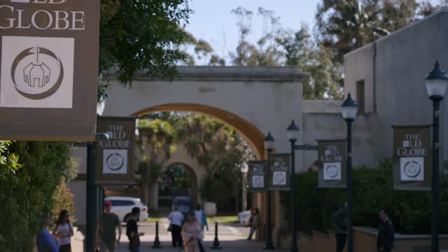 A park, the buildings and traffic in Balboa Park, with people walking.