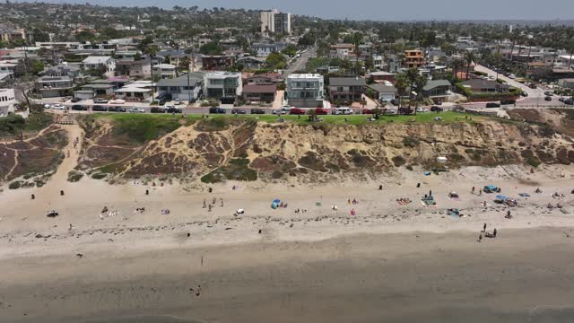 Aerial view of the beach, the ocean and homes in Pacific Beach, with a crowd gathered.