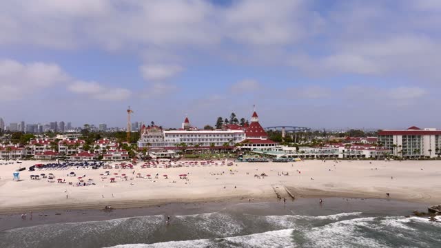 Aerial view of the beach, the bridge and the skyline at Coronado Beach, with people walking.