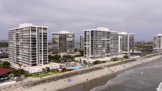 Aerial view of the beach, the ocean and homes at Coronado Beach, with people walking.
