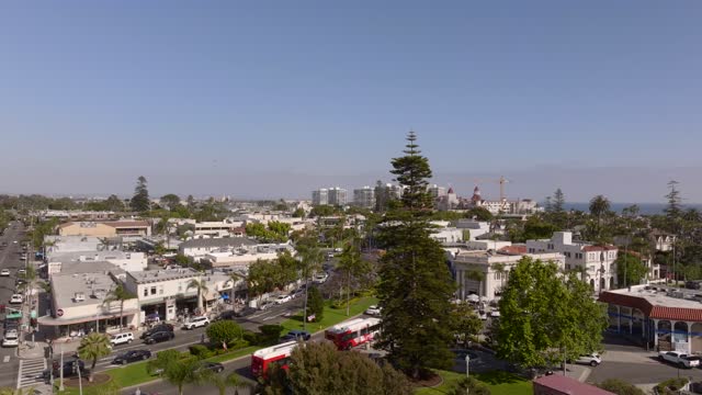 Low aerial view of the downtown streets, palm trees and homes in Coronado, with people walking.