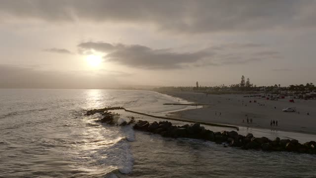 Low aerial view of the beach, the surf and palm trees at Coronado Beach, with people walking.