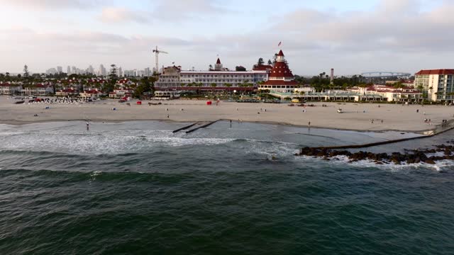 Low aerial view of the beach, the bridge and the skyline at Coronado Beach, with people walking.