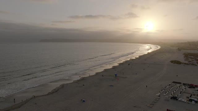 Aerial view of the beach, the surf and the ocean at Coronado Beach, with people walking.