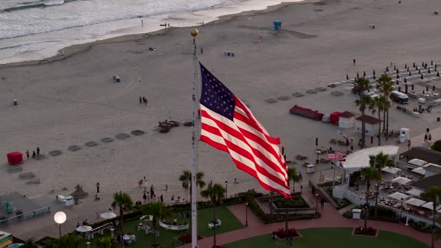 Low aerial view of the beach, the surf and palm trees at Coronado Beach, with people walking.