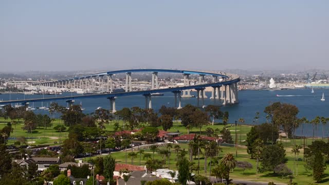 Flying towards the Coronado Bridge over the Golf Course and Glorietta Bay in San Diego during twilight | Drone Video
