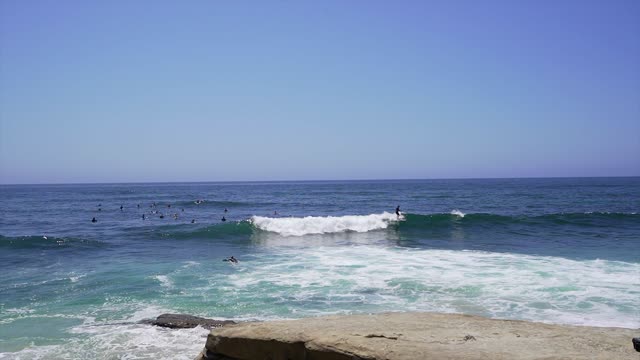 Elevated view of the beach, the surf and the ocean at Windansea, with surfers out.