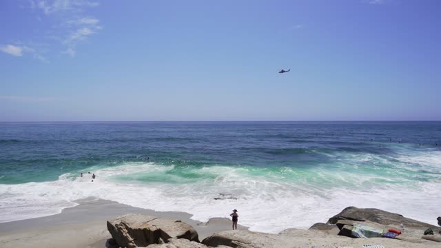 Elevated view of the beach, the surf and the ocean at Windansea, with swimmers in the water.