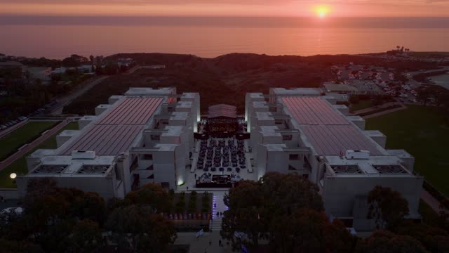 Aerial view of the country inland, the ocean and the buildings at Black’s Beach, with a crowd gathered.