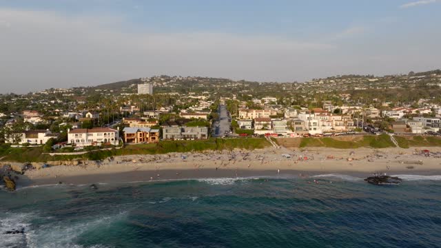 Aerial view of the beach, the surf and palm trees at Beach Barber Tract, with a crowd gathered.