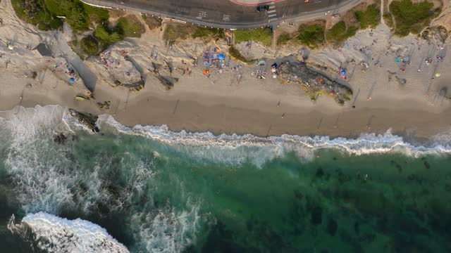 Aerial view of the beach, the surf and the ocean at Beach Barber Tract, with a crowd gathered.