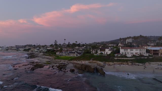 Low aerial view of the beach, palm trees and the ocean at Beach Barber Tract, with people walking.