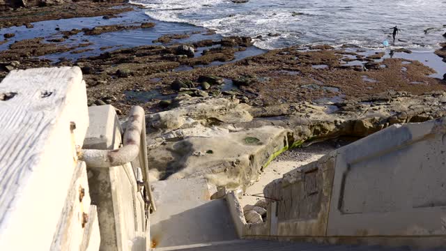 Elevated view of the cliffs, the surf and the ocean at Bird Rock, with people walking.