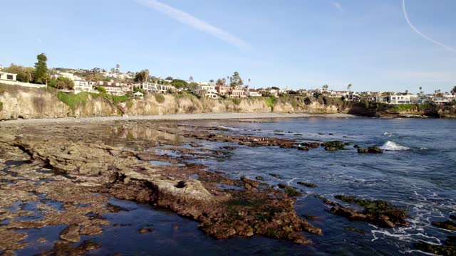 Low aerial view of the cliffs, the ocean and homes at Bird Rock.