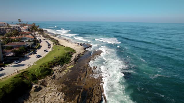 Aerial view of the cliffs, the surf and palm trees at La Jolla Cove.
