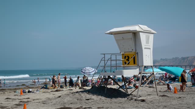The beach, the surf and the pier at La Jolla Shores, with a crowd gathered.