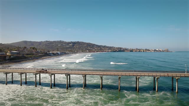 Low aerial view of the beach, the surf and the pier at La Jolla Shores.