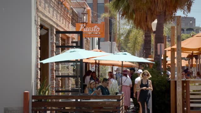 The downtown streets, palm trees and the buildings at La Jolla Village, with people eating outside.