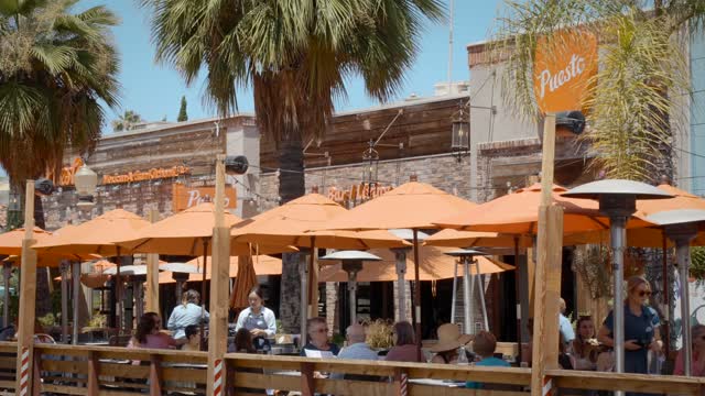 The downtown streets, palm trees and the buildings at La Jolla Village, with people eating outside.