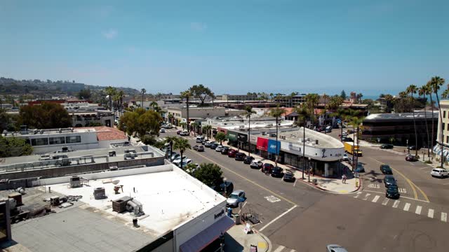 Low aerial view of the downtown streets, palm trees and the buildings at La Jolla Village, with people walking.