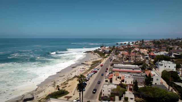 Aerial view of the beach, the surf and palm trees at Windansea, with people walking.