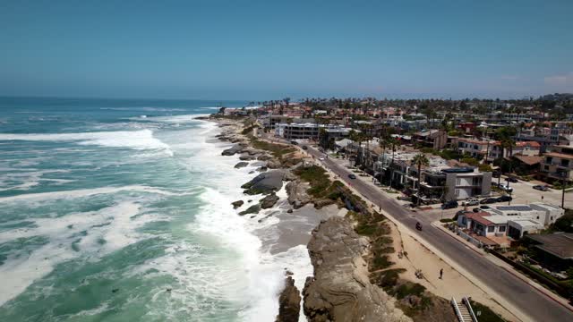 Aerial view of the cliffs, the surf and the ocean at Windansea, with people walking.
