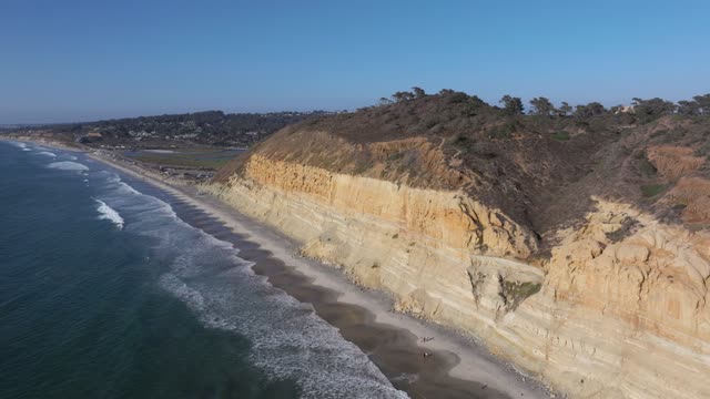 Aerial view of the cliffs, the surf and the ocean at Torrey Pines, with people walking.
