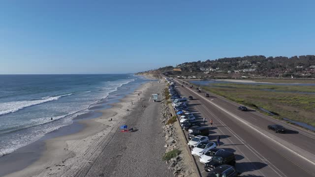 Aerial view of the beach, the surf and the ocean in Del Mar, with people walking.
