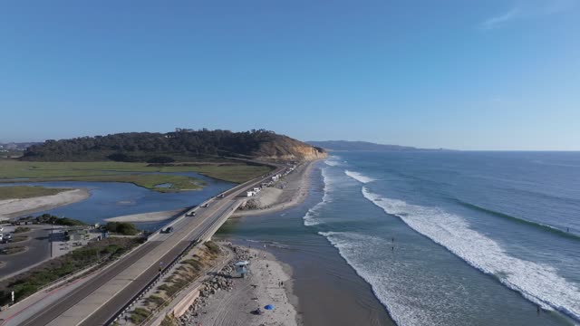 Aerial view of the cliffs, the surf and the ocean in Del Mar, with people walking.