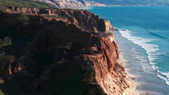 Aerial view of the cliffs, the surf and the ocean at Torrey Pines, with people walking.
