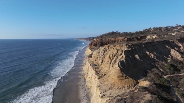 Aerial view of the cliffs, the surf and the ocean at Torrey Pines, with people walking.