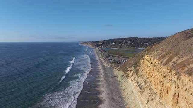 Aerial view of the cliffs, the surf and the ocean at Torrey Pines, with people walking.