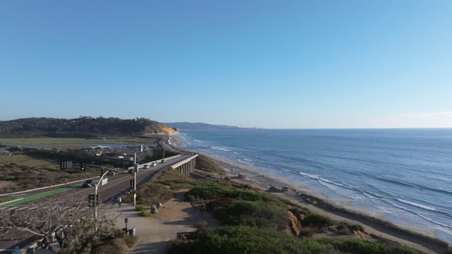 Aerial view of the cliffs, the bridge and the ocean in Del Mar, with people walking.
