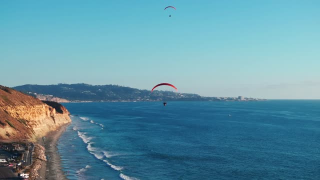 Aerial view of the cliffs, the ocean and the beach at Torrey Pines, with a crowd gathered.