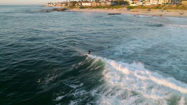 Low aerial view of the beach, the surf and the ocean at Beach Barber Tract, with surfers out.