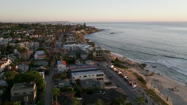 Aerial view of a residential street, palm trees and the ocean at Beach Barber Tract, with people walking.