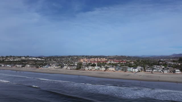 Aerial view of the beach, the surf and the ocean in Del Mar, with people walking.