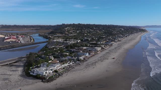 Aerial view of the beach, the surf and palm trees in Del Mar, with people walking.