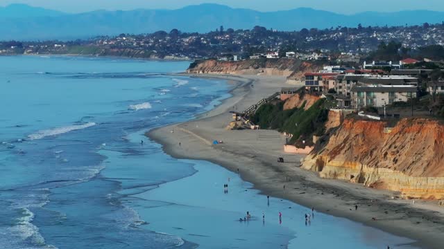 Aerial view of the beach, the surf and the ocean at Del Mar Dog Beach, with people walking.