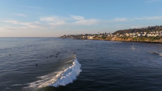 Low aerial view of the beach, the surf and the ocean at Bird Rock, with surfers out.
