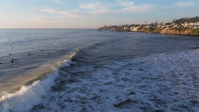 Low aerial view of the beach, the surf and the ocean at Bird Rock, with surfers out.