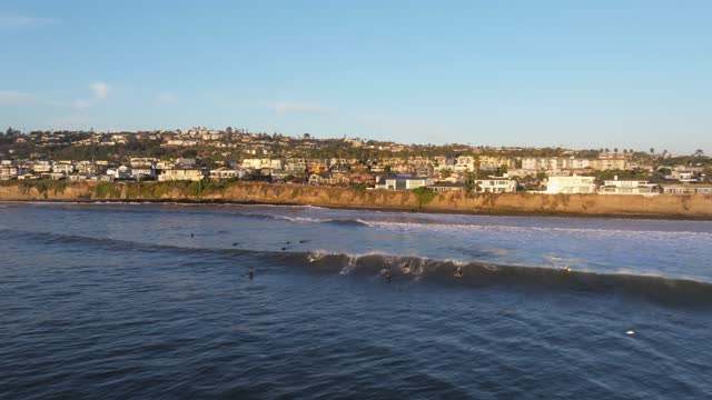 Low aerial view of the beach, the surf and the ocean at Bird Rock, with surfers out.