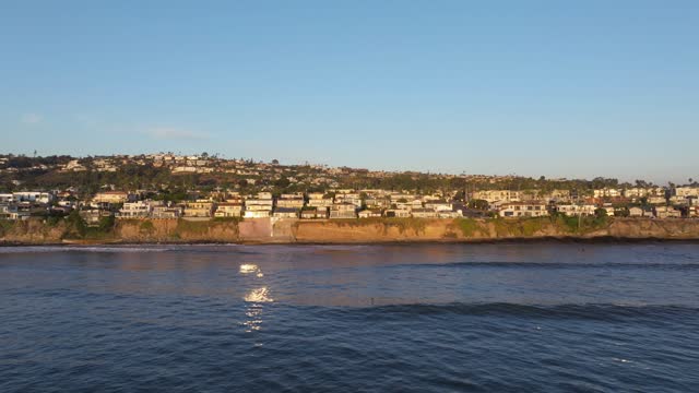 Low aerial view of the cliffs, the ocean and homes at Bird Rock.