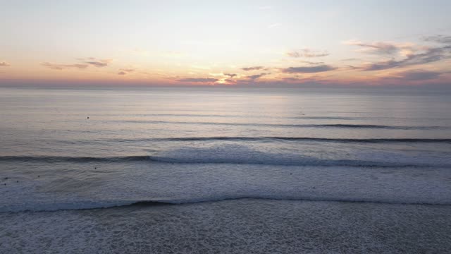 Low aerial view of the beach, the surf and the ocean at Bird Rock, with surfers out.